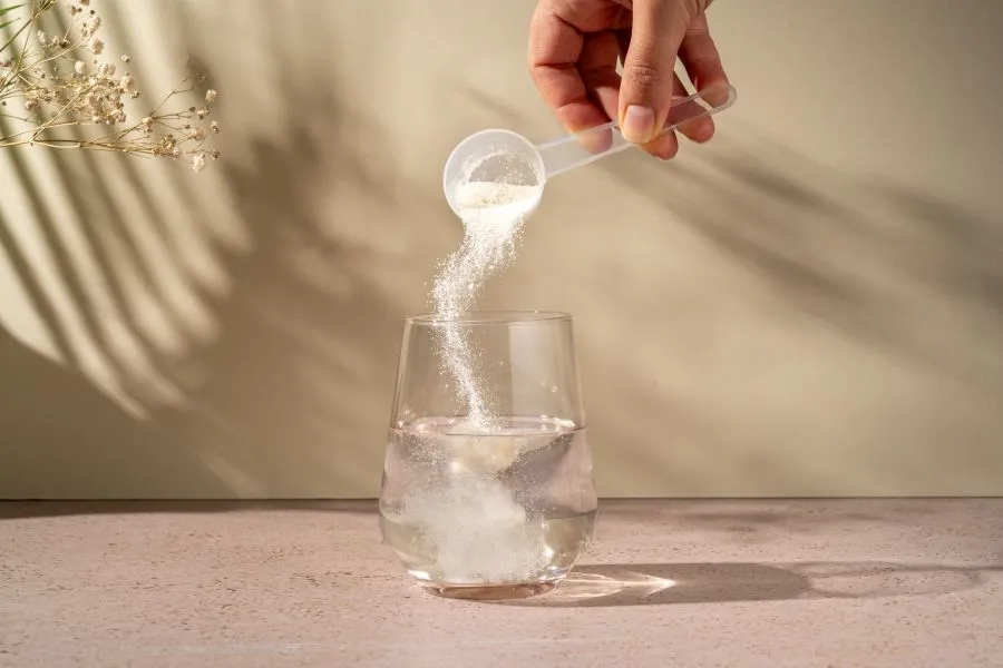 person pouring creatine into glas of water